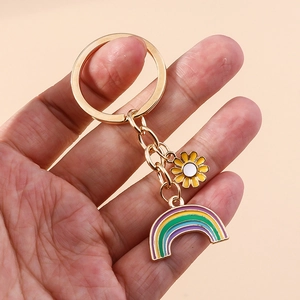 Rainbow and daisy floral keychain with golden metal clasp held against pink background