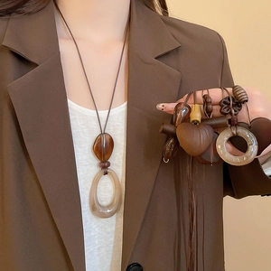 Macro shot of vintage resin heart and oval pendants on a long ethnic style necklace