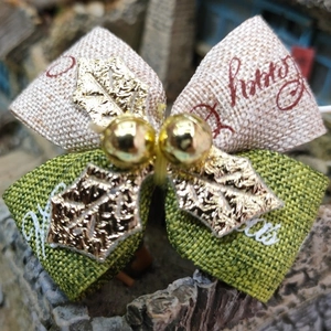 Detail of green and beige burlap Christmas bow with gold leaf and Merry Christmas print