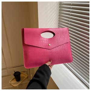 Detail of rose red crocodile embossed tote bag featuring a gold metal button closure