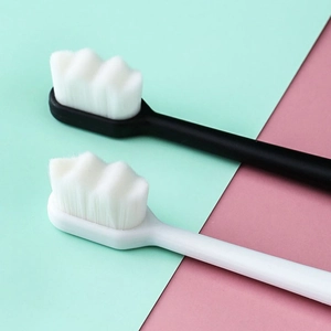 Black and white soft nano toothbrushes with wavy bristles on a mint green and pink background