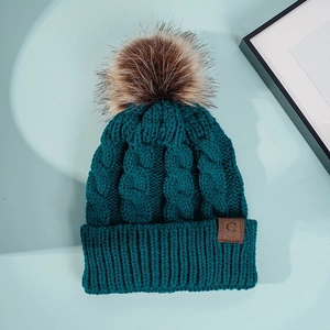 Dark green chunky cable knit beanie with faux fur pompom and leather 'C' patch