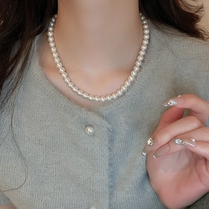 Close-up of elegant single strand white pearl necklace worn on model neck for styling