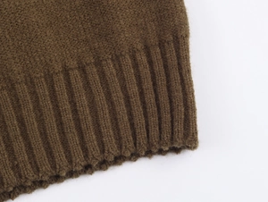 Gros plan détaillé du gilet en maille marron montrant la texture de l'ourlet côtelé