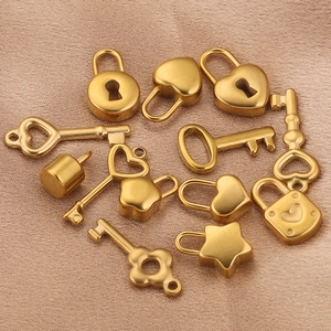 Detailed shot of golden heart, star, and square lock charms with tiny keys on beige silk fabric