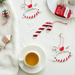 Bezaubernde Weihnachtsanhänger aus Metall mit Schaukelpferd und Zuckerstange auf Schneeoberfläche