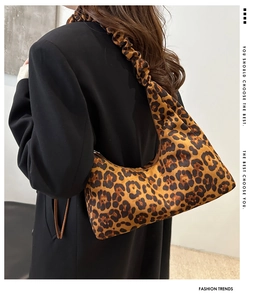 Gros plan du sac hobo léopard avec bandoulière plissée sur un costume noir élégant