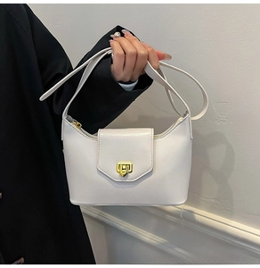 Detail of white leather underarm bag with gold geometric clasp and smooth zipper texture
