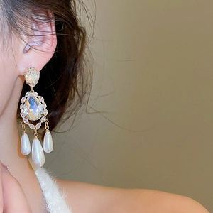 Detail view of gold-plated vintage drop earrings with sparkling crystals and three pearls