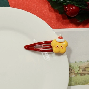 Detailed shot of a red Christmas hair clip with a yellow smiling star on a plate