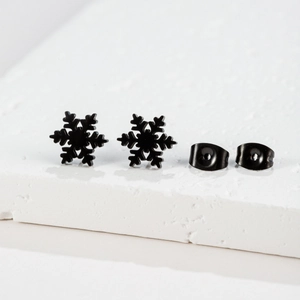 Close-up of minimalist black snowflake stud earrings with matching metal butterfly backs