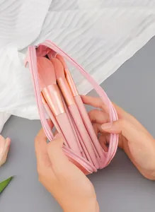 Detailed view of pink makeup bag with wide opening and a set of professional brushes