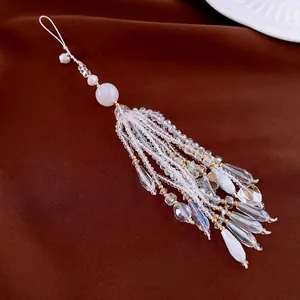 Elegant beaded phone strap with white crystals, pearls and golden tassels on velvet background