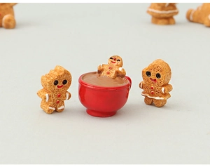 Detailed view of miniature gingerbread figures with one sitting in a red cup of cocoa