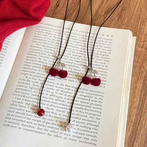 Close-up of flocking cherry pendants on pearl and bead necklaces over an open book