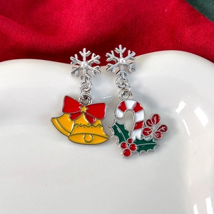 Makro-Detail von Emaille-Weihnachtsohrringen mit Schneeflocken und Stechpalme auf Keramik