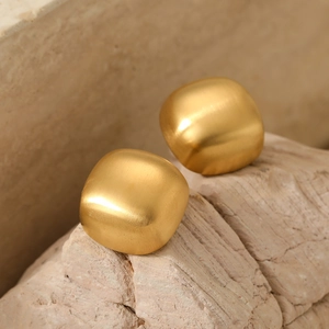 Orecchini a perno geometrici quadrati in oro con finitura opaca su sfondo di pietra