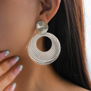 Detail of silver hollow round earrings with textured metallic finish on model