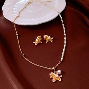 Detailed close-up of unicorn jewelry set with orange zircon and white pearls on silk fabric