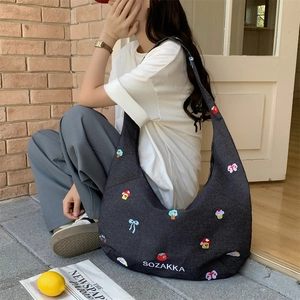 Detailansicht der dunkelgrauen Denim-Hobo-Tasche mit bunten Stickereien und weißer Aufschrift