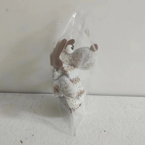 Detail of knitted Christmas dog plush pendant with gray and white stripes in packaging