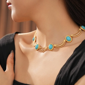 Detail of vintage gold necklace with oval turquoise stones on a layered chain model view