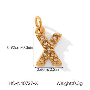 Détail macro d'un pendentif lettre X plaqué or avec des pierres de zircone claires