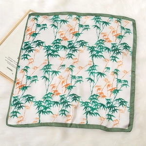 Detail of silk square scarf featuring elegant bamboo leaf prints on plush background