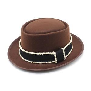 Brown wool bowler hat with black wavy ribbon and white bead trim on white background