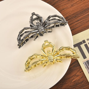 Detail view of spider hair claws in gold and gun black alloy on a ceramic plate