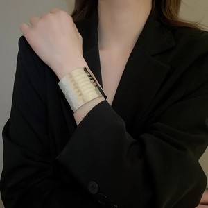 Detail of wide metallic cuff bracelet with irregular hammered texture on model