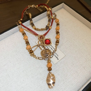 Detail of bohemian layered necklace with red stone, butterfly coin, and metal leaf charms