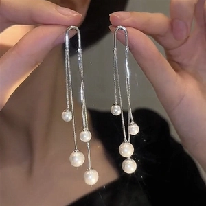 Detail view of long silver tassel earrings with white pearls and U-shaped ear hooks