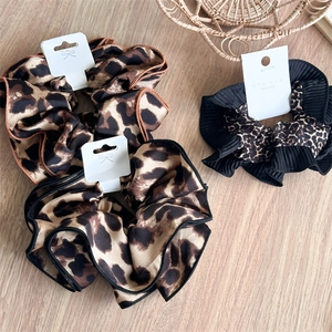 Close-up of three leopard print hair scrunchies on wood with detailed sewing texture
