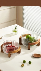 Detailed view of striped glass fruit bowl with a natural solid wood base on a desk