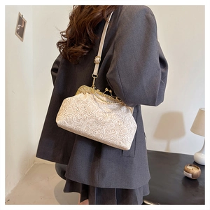 Detailed view of cream embossed floral handbag with vintage metal clasp on a model