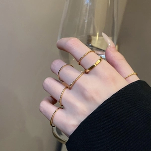 Close-up of minimalist gold layered rings styled on model hand with elegant glass decor