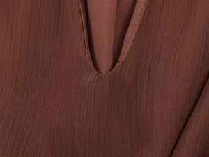 Detailed macro view of V-shaped stitching on dark reddish-brown chiffon fabric