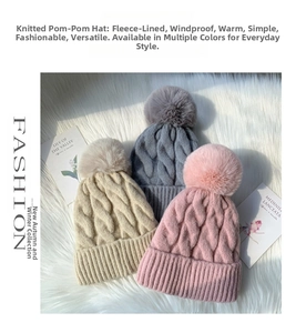 Close-up of thick cable knit beanies with faux fur pom-poms showing warm fleece lining