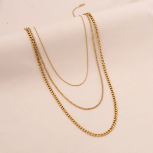 Detail of three-layer gold necklace featuring snake, bead, and Cuban link chain styles