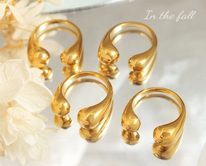 Macro shot of four 18k gold plated stainless steel teardrop rings with mirror reflection