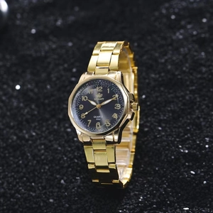 Detail of a ladies gold quartz watch with black dial and luminous particles background