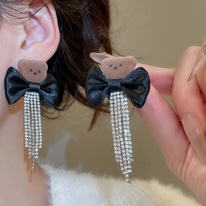 Close-up of bear earrings with black ribbon bow and sparkling rhinestone tassels