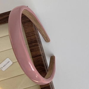 Close-up of a padded pink headband with a glossy finish on a wooden jewelry tray