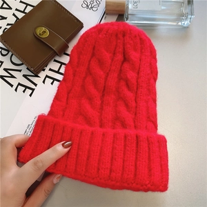 Close-up of red cable knit beanie texture with lifestyle props for winter warmth