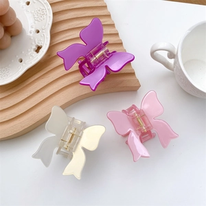 Three butterfly-shaped hair claws in purple, pink, and beige gloss acetate finish