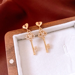 Close-up of 18k gold plated key pendant earring with sparkling rhinestones in a gift box