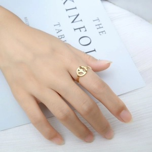 Close-up of minimalist gold peace sign ring worn on finger with kinfolk magazine background