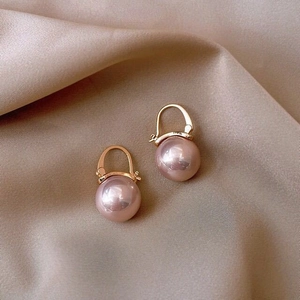 Detailed macro of pink pearl earrings with gold-plated leverback hooks on silk fabric