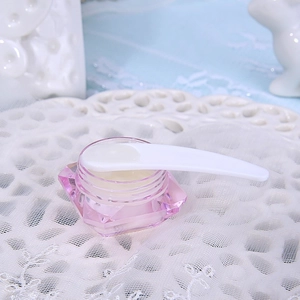 Pink diamond-cut cosmetic jar with a white plastic facial mask scoop in a decorative tray